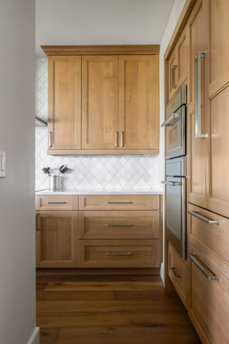 0S3A0622_ Kitchen with natural wood cabinetry, built-in wall ovens and scallop tile backsplash