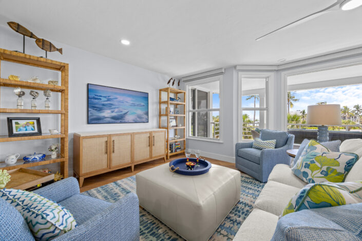 lands-end-penthouse-0S3A0308 Coastal living room with rattan étagères, cane-front media console and blue accent chairs