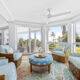 Captiva Island penthouse living room with wraparound windows, blue upholstered seating and palm views