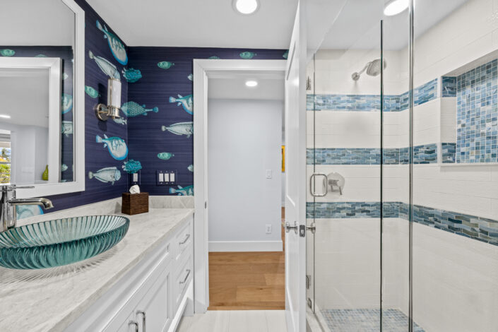 lands-end-penthouse-0S3A0437 Bathroom with fish wallpaper, glass vessel sink and blue-banded tile shower